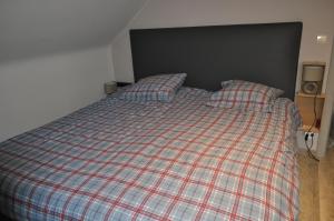 a bed with a plaid blanket and two pillows at Bon séjour in Theux