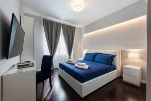 sypialnia z niebieskim łóżkiem, biurkiem i telewizorem w obiekcie Ponte Vecchio Deluxe Apartments we Florencji +37 zdjęć