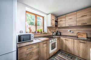 a kitchen with wooden cabinets and a microwave at Chata Partizán in Liptovský Ján