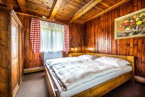 a bedroom with a bed in a wooden room at Chata Partizán in Liptovský Ján