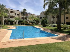a swimming pool in a resort with palm trees and buildings at RODA Golf & Beach Resort Wonderful Ground Floor Apartment in Roda