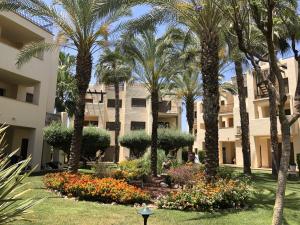 a park with palm trees and flowers in front of a building at RODA Golf & Beach Resort Wonderful Ground Floor Apartment in Roda