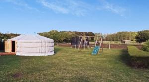 uma grande tenda branca num quintal com um baloiço em Yourte A bourlon em Bourlon