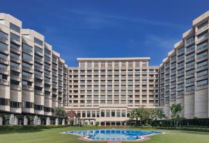 - un grand bâtiment avec une piscine en face dans l'établissement Hyatt Regency Delhi, à New Delhi