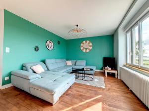 salon z niebieską kanapą i telewizorem w obiekcie Au Mont Chez Vous #Jacuzzi et Vue Mont-St-Michel# w mieście Huisnes-sur-Mer