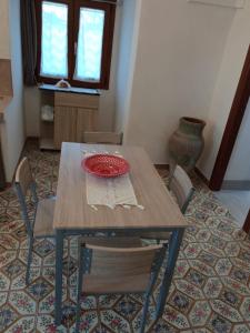 La casa dei nonni في بانتيليريا: طاولة خشبية عليها كراسي وصحن احمر