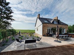 dom z patio z krzesłami i stołem w obiekcie Au Mont Chez Vous #Jacuzzi et Vue Mont-St-Michel# w mieście Huisnes-sur-Mer