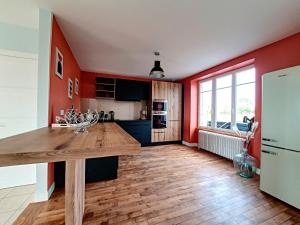 a kitchen with red walls and a wooden counter top at Au Mont Chez Vous #Jacuzzi et Vue Mont-St-Michel# in Huisnes-sur-Mer