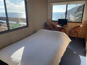 1 dormitorio con 1 cama blanca grande y 2 ventanas en 1棟貸し tbtランド 定員最大12名 en Shodoshima