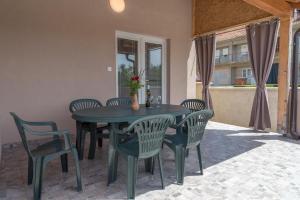 a green table and chairs on a patio at Apartmani Kržak in Nin