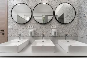 a bathroom with two sinks and two mirrors at Hostel Antique in Pula