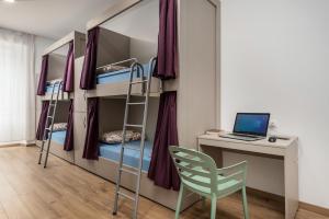 a room with bunk beds with a desk and a laptop at Hostel Antique in Pula