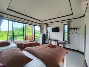 3 camas num quarto com vista para uma varanda em บ้านแม่อุทัยธานี Baanmae Uthaithani em Uthai Thani