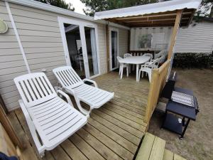 a deck with white chairs and a table and a grill at Mobile Home 4 pers Bois Dormant 494 in Saint-Jean-de-Monts