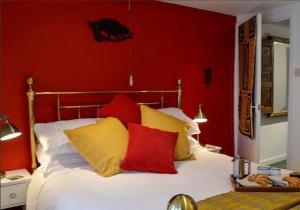 a red bedroom with a bed with yellow and red pillows at Cosy holiday cottage in Crickhowell. in Llangattock