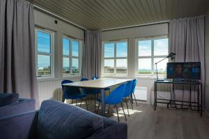 a living room with a table and chairs and windows at Grønnbuene Rorbu Hotel in Andenes