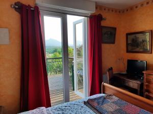 a bedroom with a large window with red curtains at Le Petit Chalet du Hérisson- Panorama unique ! in Montespan