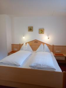 a bedroom with a bed with white sheets and pillows at Landhaus Wieser in Ramsau am Dachstein