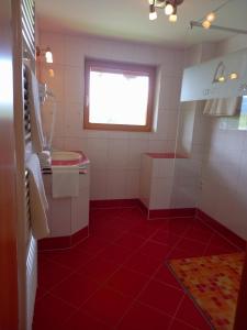 a bathroom with a red tiled floor and a window at Landhaus Wieser in Ramsau am Dachstein