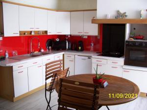 a kitchen with white cabinets and a table and a sink at La Salamandre in Écouflant
