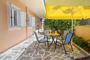 a patio with a table and chairs with a yellow umbrella at ΒΙΛΑ ΜΠΟΥΜΠΟΥΛΙΝΑ in Sami