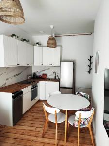 una cocina con mesa y sillas y una cocina con armarios blancos. en Centrum Apartament Przytulny, en Świdnica