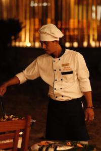 Wild Beach Phu Quoc Resort في فو كووك: شيف واقف امام طاولة يحضر الطعام