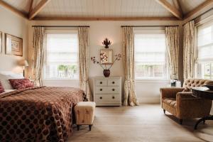 a bedroom with a bed and a chair and windows at Inn on the Lake in Broek in Waterland