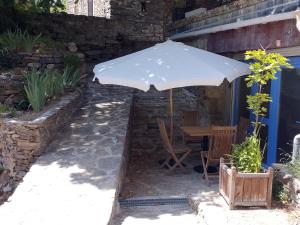 a table with an umbrella next to a building at Studio La maison bleue in Saint-Mélany