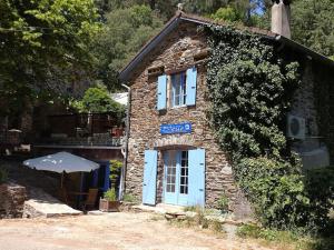 a stone building with blue doors and an umbrella at Studio La maison bleue in Saint-Mélany