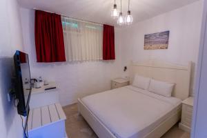 a small bedroom with a white bed and red curtains at Kokopelli Alacati in Alaçatı