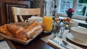 a table with a tray of bread and orange juice at Manoir de Pierreville in Audouville-la-Hubert