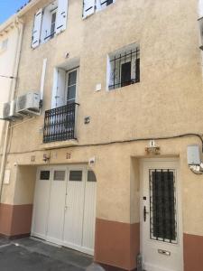 a building with two white doors and a balcony at Agréable maison au cœur du village in Argelès-sur-Mer