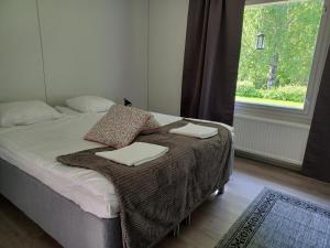 a bedroom with a bed with a blanket and a window at Kartanohostel AnnaCatharina in Savonlinna