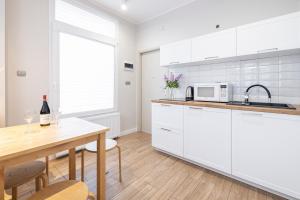 a kitchen with white cabinets and a table with a sink at Apartamenty Baltic in Sopot