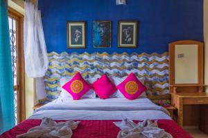 a bedroom with a large bed with pink pillows at Villa Candolim in Candolim