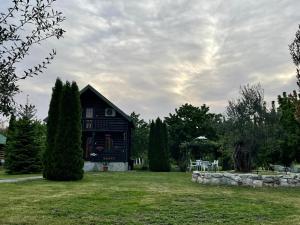 a black house on a grassy yard with trees at Wooden House in Podgorica