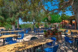 an outdoor restaurant with blue chairs and tables and trees at Pounta Apartments in Vingláfia