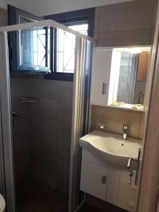 a bathroom with a sink and a mirror and a window at Pounta Apartments in Vingláfia