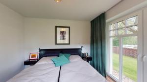 um quarto com uma cama e uma grande janela em Landhaus Lindenhof, Insel-Juwel em Wangerooge