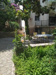 un patio con mesa y sillas bajo un árbol en Apartmani Abeona, en Budva