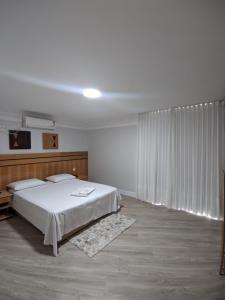 sypialnia z białym łóżkiem i dużym oknem w obiekcie Horto Executivo Hotel w mieście Ipatinga