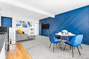 a living room with a blue accent wall and a table and chairs at The Woodfield - stunning modern 2 bed apartment - TV in every bedroom! in Swansea