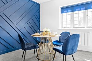 a dining room with blue chairs and a table at The Woodfield - stunning modern 2 bed apartment - TV in every bedroom! in Swansea