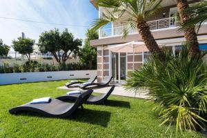 a row of chaise lounges in the grass near a building at Villa Velvet in Villeneuve-Loubet