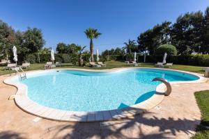 una piscina en un patio con sillas y árboles en Villa Mamma Grazia Rooms, en San Vito dei Normanni