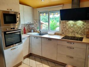 a kitchen with a stove and a sink and a window at Chalet charmant à Saint-Joseph avec terrasse et jardin in Saint-Joseph