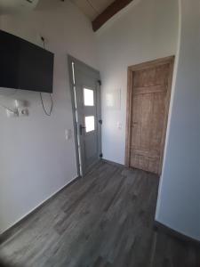 an empty room with a door and a wooden floor at ΚΥΘΝΟΣ LAREROOMS in Mérikhas
