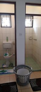 a bathroom with a toilet and a shower and a basket at Lyneks Cosy Apartment in Mombasa