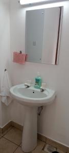 ein Badezimmer mit einem weißen Waschbecken und einem Spiegel in der Unterkunft Lyneks Cosy Apartment in Mombasa